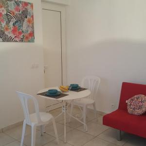 a dining room with a white table and chairs at Studio Pleine Nature in Les Abymes