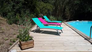 três cadeiras num deque de madeira junto a uma piscina em gite dentelles em Loriol-du-Comtat