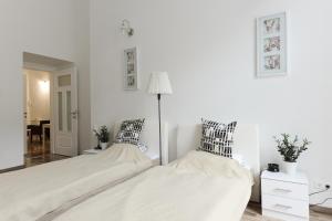 ブダペストにあるSpacious Evergreen Apartment in the heart of Budapestの白いベッドルーム(ベッド2台、ランプ付)