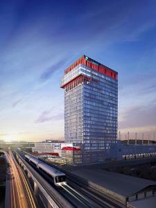 a tall glass building with a train in front of it at Marigold Sukhumvit - Free Shuttle to BTS Bearing Station in Bangkok