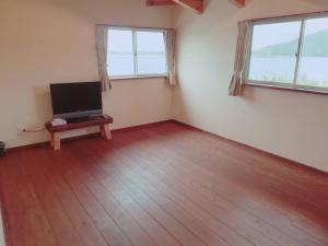 a living room with a flat screen tv and two windows at hanon～波音～ in Tatsugo