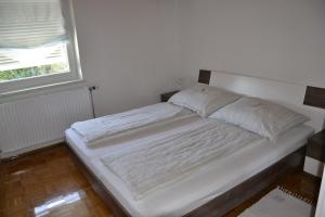 Cama blanca en habitación con ventana en Ferienwohnung Messner-Schauer, en Sankt Kanzian