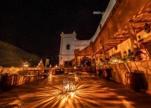 a building with a table and chairs at night at Hotel Riad Bahammou in Aït Idaïr