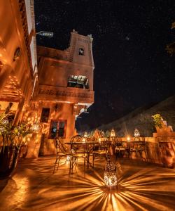 eine Terrasse mit einem Tisch und Stühlen in der Nacht in der Unterkunft Hotel Riad Bahammou in Aït Idaïr