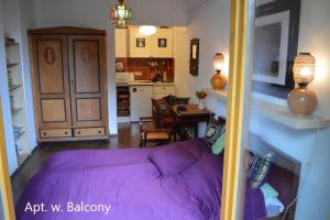 a bedroom with a purple bed and a kitchen at Cozy studio at the Castle in Budapest