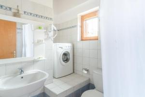 a white bathroom with a washing machine and a sink at Maniatiko Village in Stoupa
