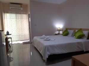 Un dormitorio con una cama con almohadas verdes y una ventana en Connect Apartment, en Nakhon Ratchasima