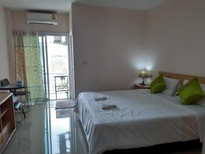 1 dormitorio con 1 cama grande con almohadas verdes en Connect Apartment, en Nakhon Ratchasima
