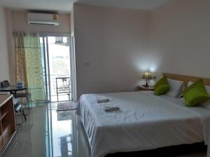 a bedroom with a large bed with green pillows at Connect Apartment in Nakhon Ratchasima