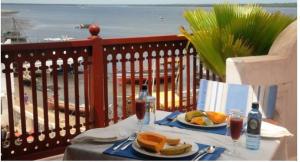 a table with two plates of food on a balcony at Beytsalam in Lamu