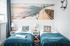 a bedroom with two beds and a picture of a boat at Błękitny Żagiel in Gdynia