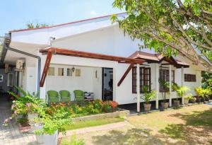 カトゥナーヤカにあるHOSTEL KATUNAYAKE At COLOMBO AIRPORT TRANSITの庭に緑の椅子が置かれた白い家