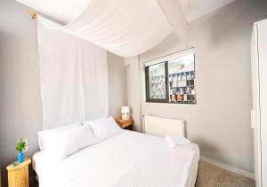 a white bedroom with a white bed and a window at Live in Athens, PSYRRI Central Apartments in Athens