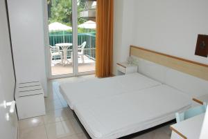 Cette chambre comprend un lit blanc et un balcon. dans l'établissement Residence Alexander, à San Benedetto del Tronto