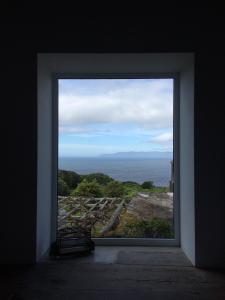 a window in a room with a view of the ocean at CASA DO CASTANHEIRO in Santo Antonio