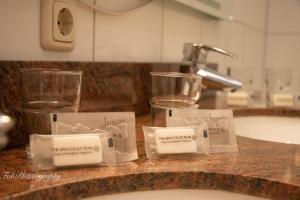 Hotel 2000 Valkenburg في فالكنبورخ: منضدة الحمام بها كأسين ومغسلة