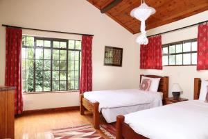 two beds in a bedroom with red curtains at Francolin Cottage at Great Rift Valley Lodge & Golf Resort Naivasha in Naivasha
