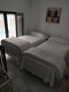 - 2 lits dans une chambre avec des draps blancs dans l'établissement Apartamento duplex en centro de Sevilla, à Séville