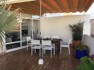 eine Terrasse mit einem Holztisch und weißen Stühlen in der Unterkunft La terraza de San Pedro in Cádiz