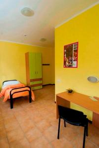 Habitación amarilla con cama y escritorio. en Casthello Ostello di Vallecamonica, en Breno