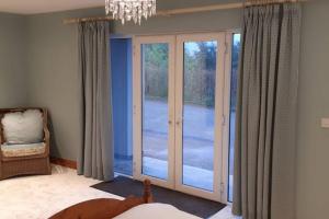 a bedroom with sliding glass doors and a chandelier at Tir na nOg - A Piece of Heaven in Bantry