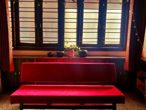 a red bench sitting in a room with windows at Raahgir in Nashik