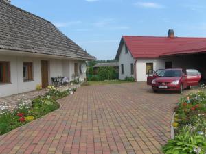 un coche rojo estacionado en una entrada entre dos casas en Talsu Pirtiņa Vijoles, en Talsi