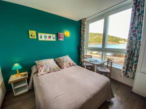 um quarto com uma cama com uma parede verde e uma janela em Appart'Hôtel LIDO au bord de l'eau em Gérardmer