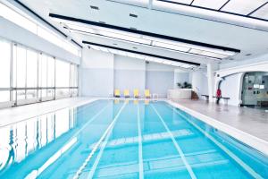 a large swimming pool with blue water in a building at Golden Tulip Porto Gaia Hotel in Vila Nova de Gaia