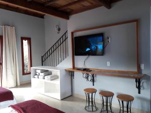 a living room with three stools and a tv on the wall at Dama 2 in Tiradentes