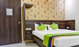 a bedroom with a large bed with green and purple pillows at Treebo Trend Royal Sun Palace MP Nagar Zone 2 in Bhopal