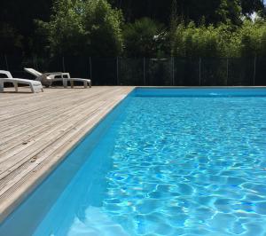 a swimming pool with blue water and two chairs at Résidence Thibaud in Toulouse
