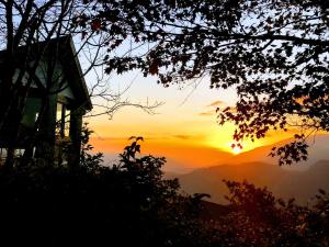 a sunset in the mountains with a house at Top Cloud Villa in Renai