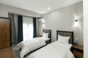 um quarto com 2 camas com lençóis brancos e uma janela em Merci Hotel em Tashkent