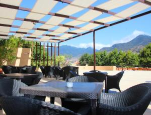 a patio with tables and chairs with mountains in the background at Dom Pedro Madeira in Machico