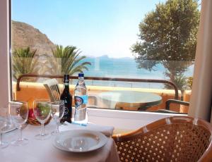 a table with wine bottles and glasses and a window at Dom Pedro Madeira in Machico
