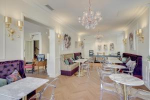 a living room with tables and chairs and a chandelier at Hotel Bleu de Mer in Bordeaux