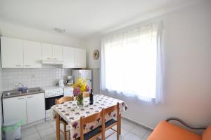 eine Küche mit einem Tisch mit Blumen darauf in der Unterkunft Apartmani Badurina - Maslina in Lun