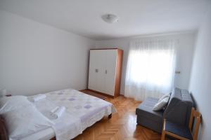 ein Schlafzimmer mit einem Bett, einem Stuhl und einem Fenster in der Unterkunft Apartmani Badurina - Maslina in Lun