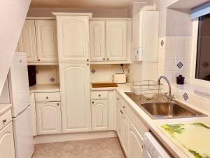 a white kitchen with white cabinets and a sink at Hawkshead Cottage in Glossop