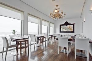 uma sala de jantar com mesas e cadeiras brancas e um lustre em Golden Tulip Porto Gaia Hotel em Vila Nova de Gaia