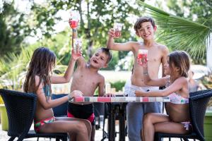 a group of people sitting around a table holding up drinks at Camping Les Peupliers in La Flotte