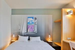 ein Schlafzimmer mit einem weißen Bett und einem Fenster in der Unterkunft B&B HOTEL Valence Sud in Valence