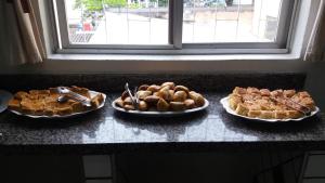 três pratos de comida num balcão ao lado de uma janela em Hotel Calcinfer em São João del Rei