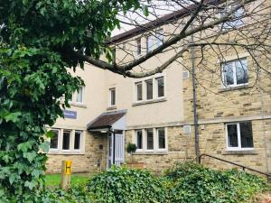 a house with a brick building and a tree at The Venue Serviced Apartments in Huddersfield