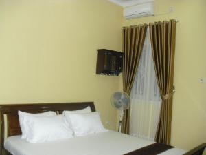a bedroom with a bed and a window with a fan at Kartika Guest House Cianjur in Tjiandjur