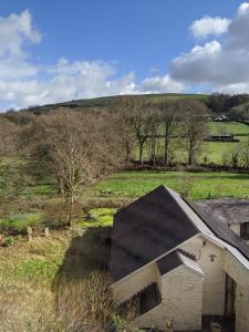 an old house with a black roof in a field at Glan Brennig in Tregaron