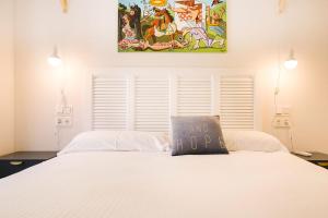 a bedroom with a white bed with a painting on the wall at Apartamentos San Marcial 28 in San Sebastián