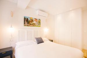 una camera da letto bianca con un letto bianco e un dipinto sul muro di Apartamentos San Marcial 28 a San Sebastián