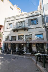 a white building with tables and chairs in front of it at Ederlezi Zoubourlou Aparthotel in Athens